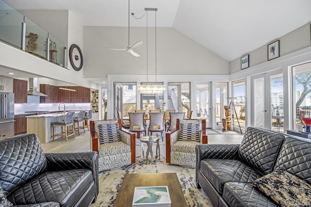 living room with sink, ceiling fan with notable chandelier, high vaulted ceiling, and french doors