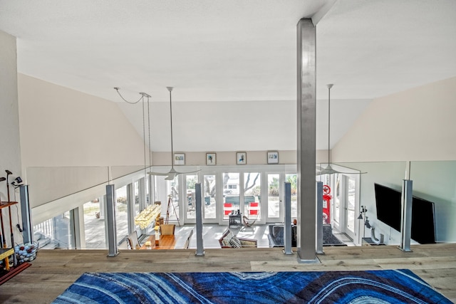 unfurnished living room with vaulted ceiling, hardwood / wood-style floors, and french doors