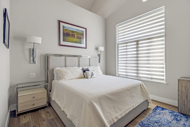 bedroom featuring dark wood-type flooring, vaulted ceiling, and multiple windows