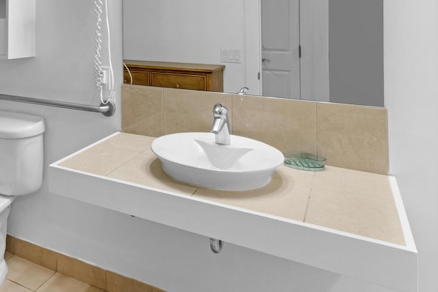 bathroom with tasteful backsplash, sink, tile patterned floors, and toilet