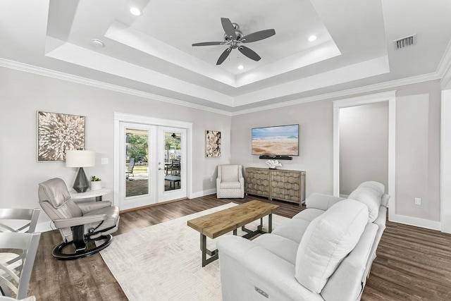 living room with a raised ceiling, ceiling fan, dark hardwood / wood-style flooring, and french doors