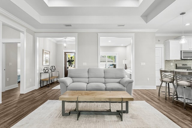 living room with a raised ceiling, ornamental molding, and dark hardwood / wood-style floors