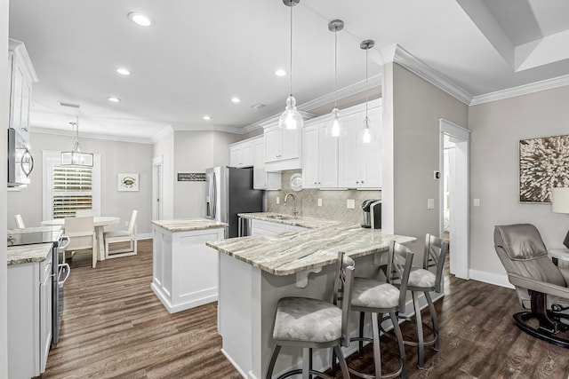 kitchen with white cabinetry, appliances with stainless steel finishes, decorative light fixtures, and a center island