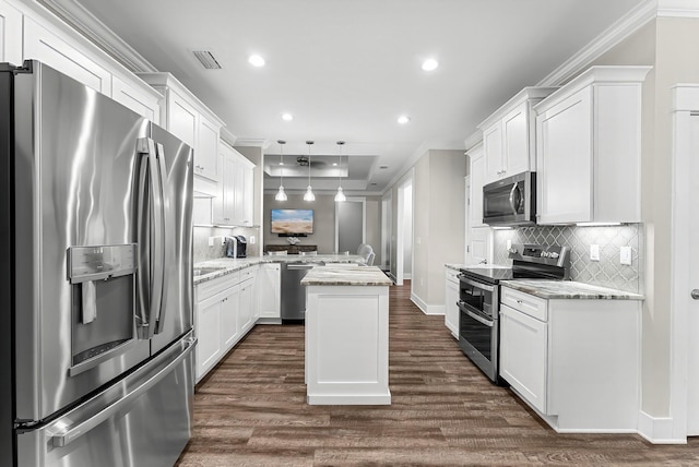 kitchen with appliances with stainless steel finishes, white cabinetry, hanging light fixtures, a center island, and light stone countertops