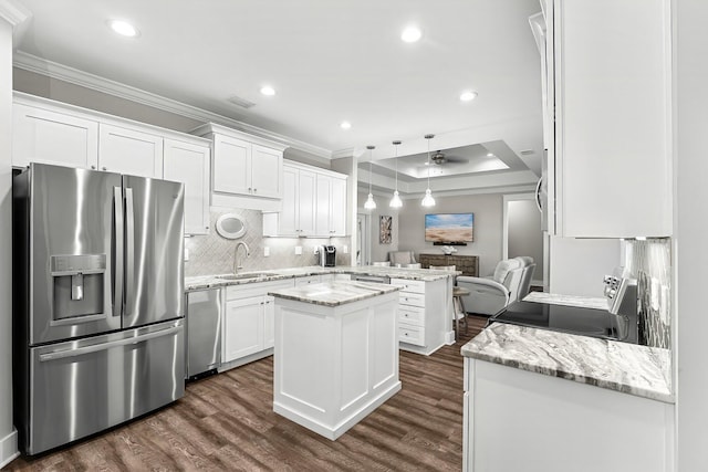 kitchen featuring stainless steel appliances, white cabinetry, light stone countertops, and a center island