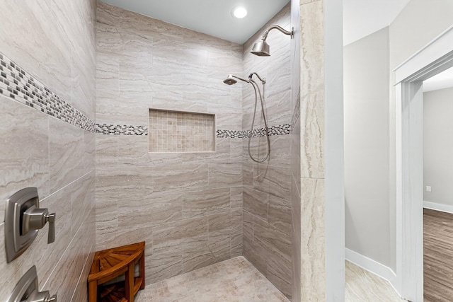 bathroom featuring hardwood / wood-style flooring and a tile shower