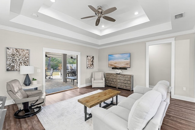 living room with hardwood / wood-style floors, a tray ceiling, and ceiling fan