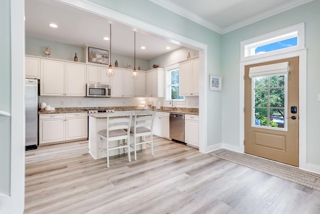 kitchen featuring decorative light fixtures, a kitchen breakfast bar, a kitchen island, stainless steel appliances, and white cabinets