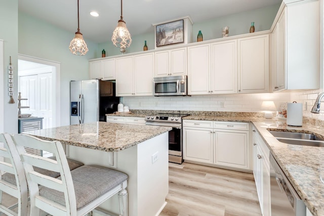 kitchen featuring white cabinetry, stainless steel appliances, sink, and hanging light fixtures