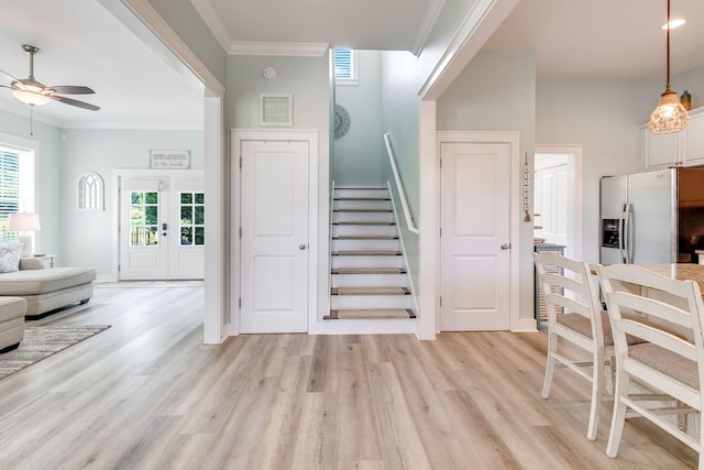 foyer entrance featuring light hardwood / wood-style flooring, ornamental molding, and ceiling fan