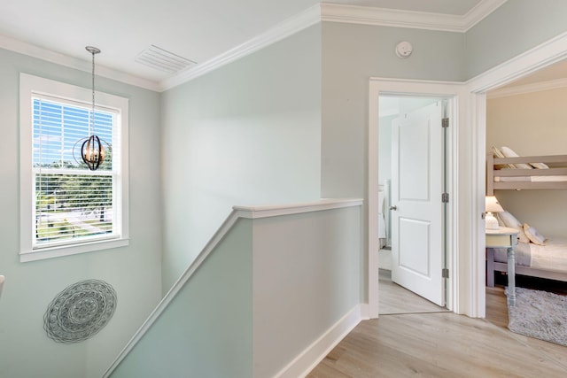 hall featuring ornamental molding, an inviting chandelier, and light wood-type flooring