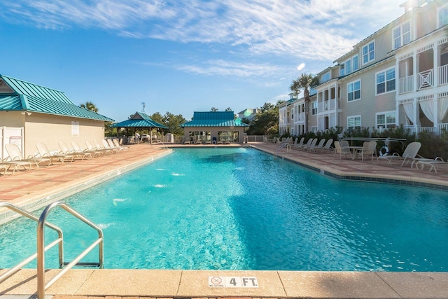 view of swimming pool with a gazebo, pool water feature, a beach view, and a patio area