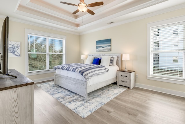 bedroom with a tray ceiling, ornamental molding, and light hardwood / wood-style floors