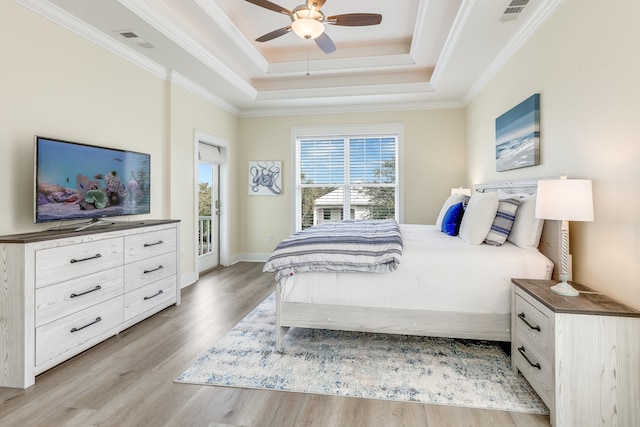 bedroom featuring ornamental molding, a raised ceiling, light wood-type flooring, and access to outside