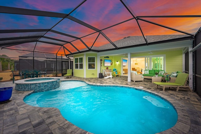 pool at dusk with an in ground hot tub, a lanai, an outdoor hangout area, and a patio