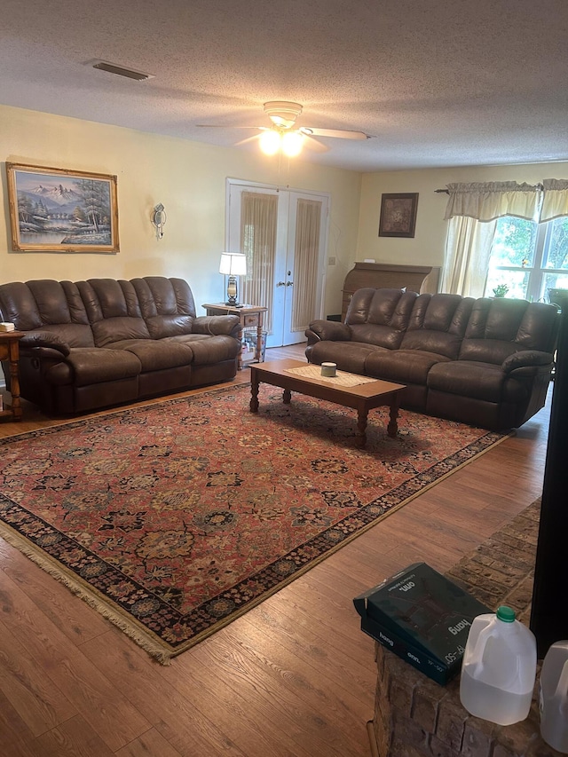 living room featuring ceiling fan, hardwood / wood-style floors, and a textured ceiling