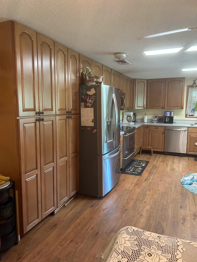 kitchen featuring hardwood / wood-style flooring, stainless steel appliances, sink, and a textured ceiling