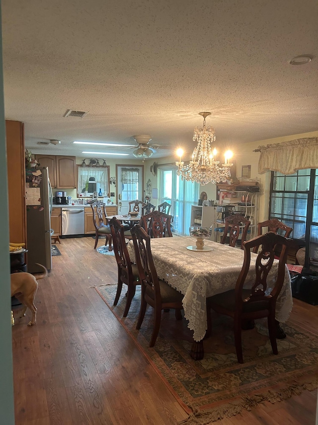 dining area with an inviting chandelier, dark hardwood / wood-style flooring, and a textured ceiling