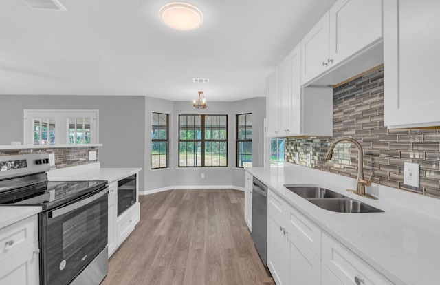 kitchen with sink, stainless steel appliances, a wealth of natural light, white cabinets, and light wood-type flooring