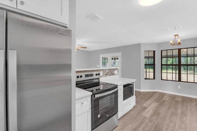 kitchen with white cabinetry, appliances with stainless steel finishes, backsplash, and light hardwood / wood-style floors