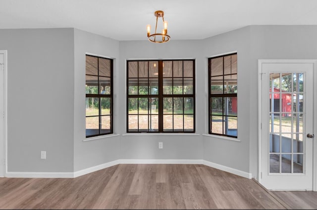 spare room featuring wood-type flooring and a chandelier