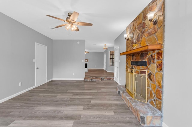 unfurnished living room featuring hardwood / wood-style floors, a stone fireplace, and ceiling fan