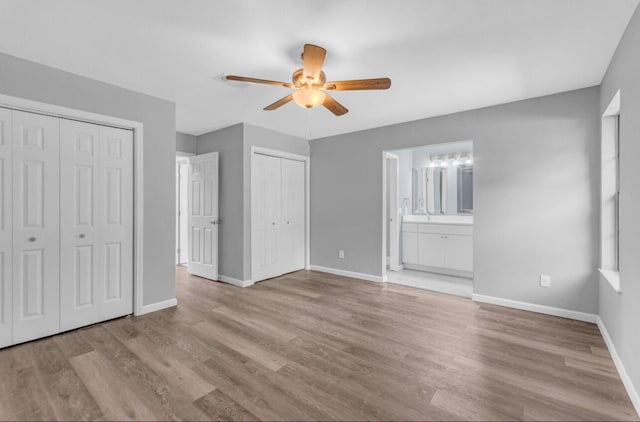 unfurnished bedroom with multiple closets, ceiling fan, ensuite bathroom, and light hardwood / wood-style floors