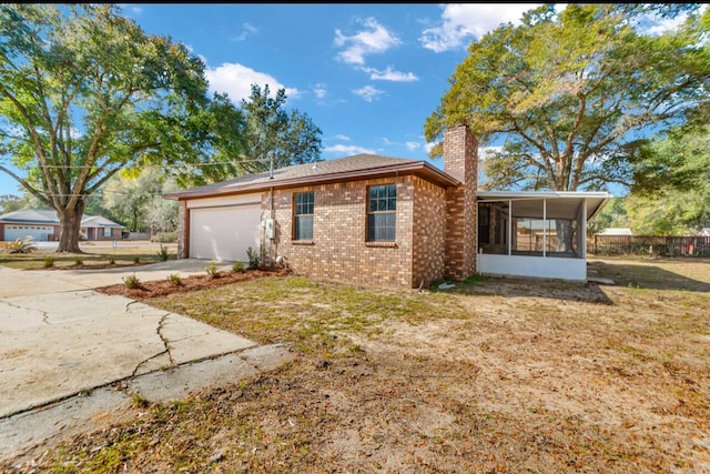 exterior space featuring a garage, a sunroom, and a yard