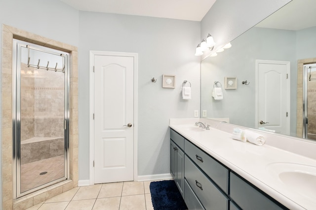 full bathroom featuring double vanity, a stall shower, a sink, and tile patterned floors