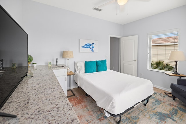 bedroom with visible vents, dark wood-type flooring, a ceiling fan, a sink, and baseboards