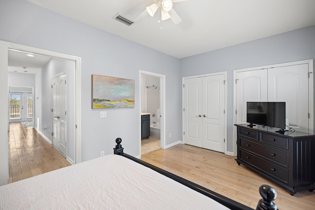 bedroom with baseboards, visible vents, ensuite bathroom, light wood-style floors, and multiple closets