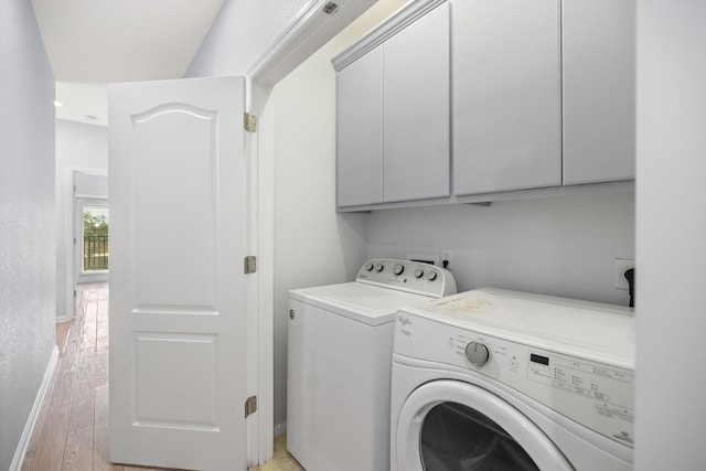 laundry room featuring cabinet space, baseboards, a textured wall, washer and dryer, and light wood-type flooring