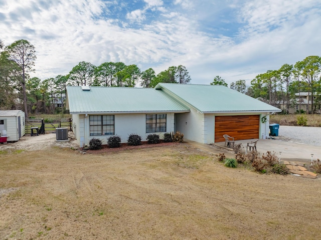 view of front of house with cooling unit, a garage, and a front yard