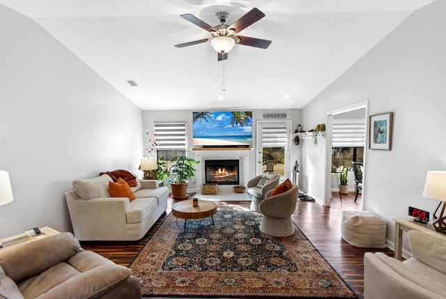 living room featuring lofted ceiling, ceiling fan, dark wood-type flooring, and a healthy amount of sunlight