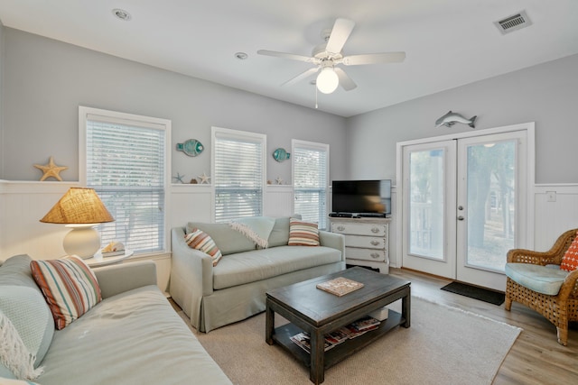 living room with ceiling fan, a wealth of natural light, light wood-type flooring, and french doors