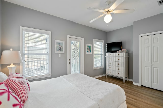 bedroom featuring multiple windows, hardwood / wood-style flooring, access to exterior, and ceiling fan