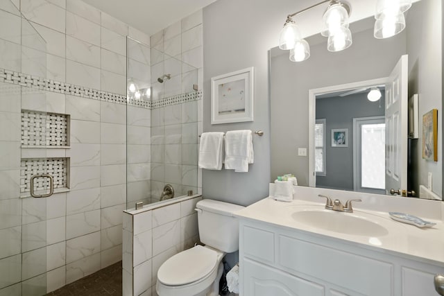 bathroom featuring tiled shower, vanity, and toilet