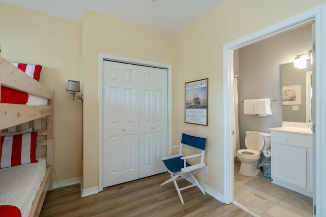 bedroom with ensuite bath, light hardwood / wood-style flooring, and a closet