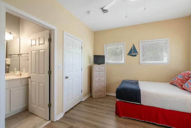 bedroom with connected bathroom and light hardwood / wood-style flooring