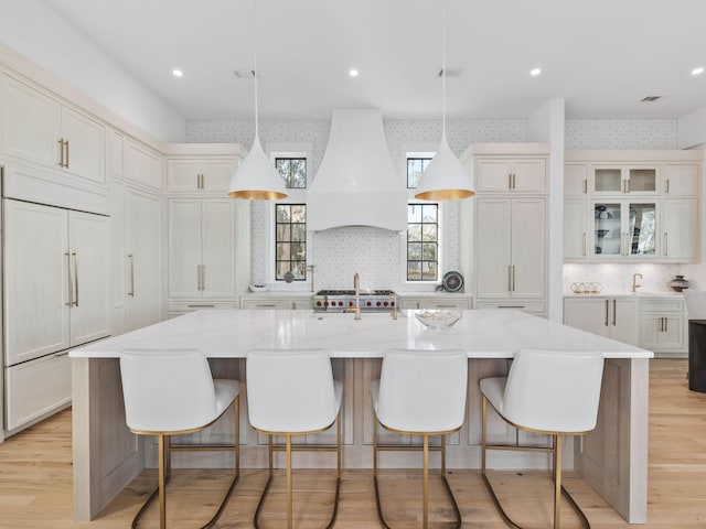 kitchen with a spacious island, decorative light fixtures, custom range hood, and premium appliances