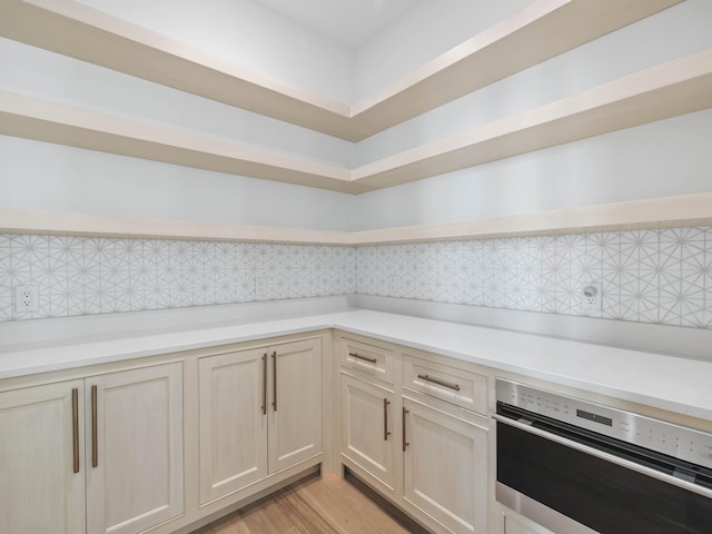 kitchen with tasteful backsplash, light hardwood / wood-style floors, and oven