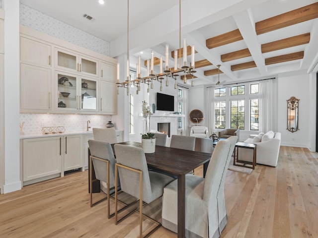 dining room featuring coffered ceiling, beam ceiling, and light hardwood / wood-style flooring