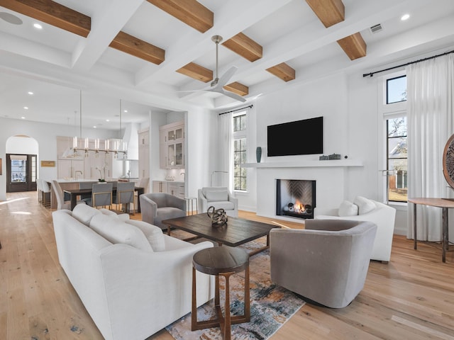 living room featuring coffered ceiling, a wealth of natural light, and light hardwood / wood-style floors