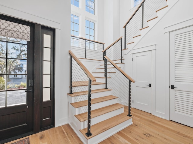 foyer entrance featuring a towering ceiling and light wood-type flooring