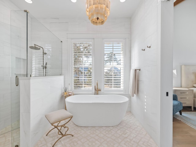 bathroom with tile walls, independent shower and bath, and an inviting chandelier