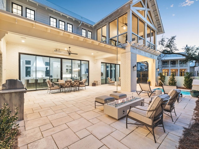 back of property featuring a fire pit, ceiling fan, a patio area, area for grilling, and a balcony