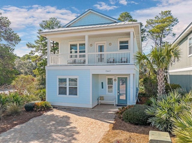 raised beach house featuring a balcony and a porch