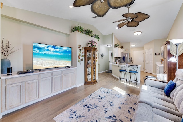 living room featuring ceiling fan, vaulted ceiling, and light hardwood / wood-style flooring