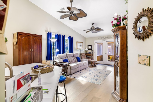 living room with a wealth of natural light, vaulted ceiling, ceiling fan, and light wood-type flooring