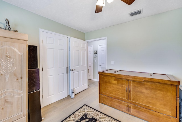 bedroom featuring ceiling fan, light hardwood / wood-style floors, and a textured ceiling